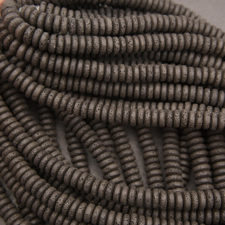 Close-up of black lava rock rondelle beads featuring flattened round shapes and distinctive volcanic pitting.