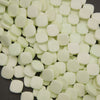 A close-up pile of small, rounded square beads in a pale mint green color, filling almost the entire frame.
