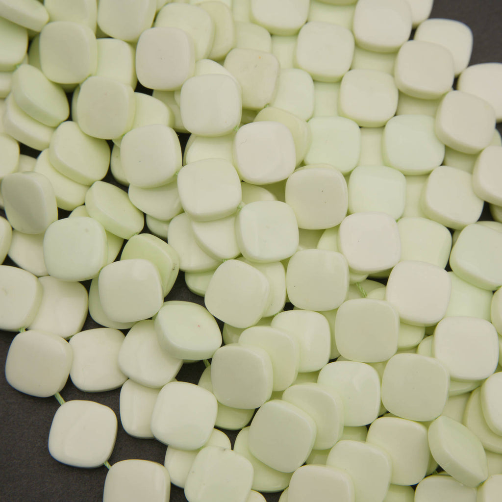 A close-up pile of small, rounded square beads in a pale mint green color, filling almost the entire frame.