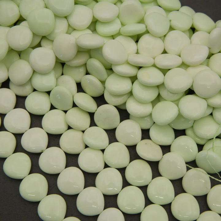 Light green button beads scattered on a dark surface