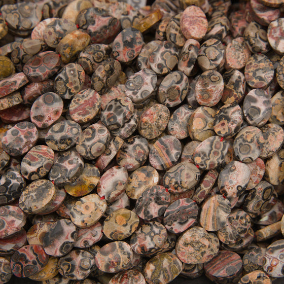 Close-up of faceted leopard skin jasper oval beads showing pink, tan and gray with dark leopard spots