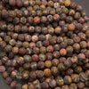 A pile of round cabochon gemstone beads featuring a marbled pattern of red, yellow, brown, and black.
