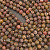 A close-up arrangement of many round stone beads in earthy mottled colors, including brown, beige, red, gray, and black, filling the frame.