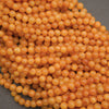 A pile of small, round, translucent orange beads on a dark gray background.