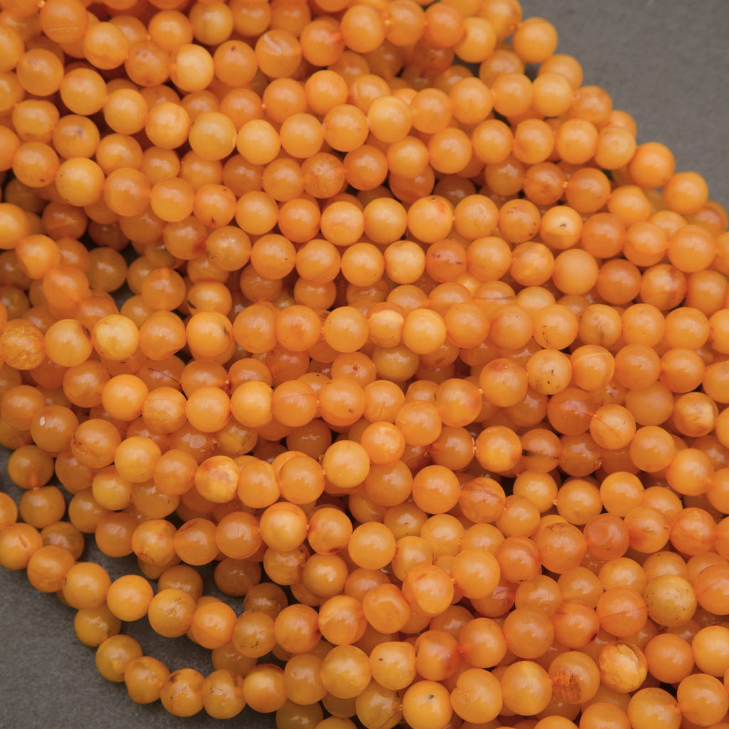 A pile of small, round, translucent orange beads on a dark gray background.