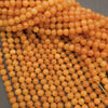 A pile of small, round, translucent orange beads strung on cords, filling the frame against a dark gray background.