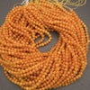 A coiled bundle of small round amber-orange beads on a dark gray background.