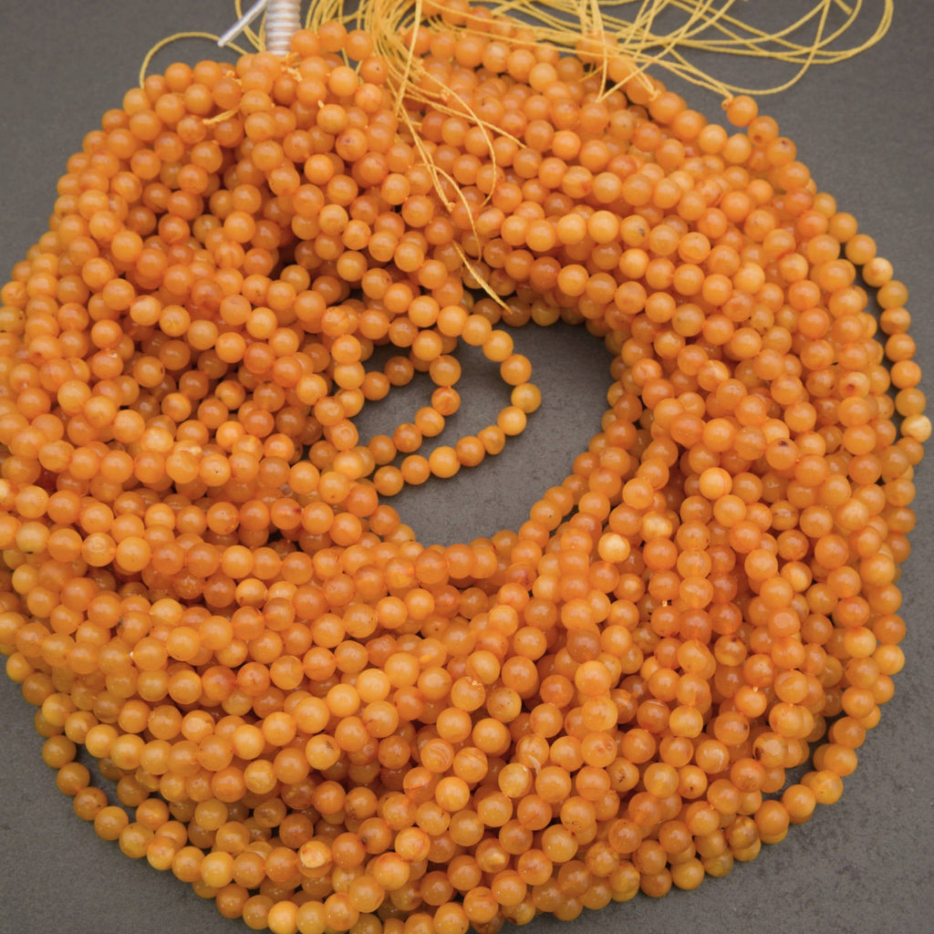 A coiled bundle of small round amber-orange beads on a dark gray background.