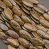 A close-up pile of polished oval gemstone beads in earthy brown, tan, and gray tones with natural marbled patterns.