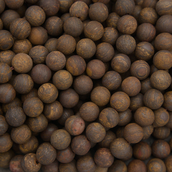 A close-up pile of small round brown beads with a mottled, textured finish.