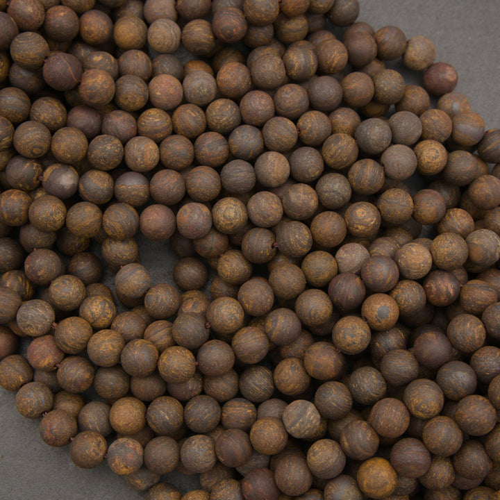 A pile of small, round wooden beads with a natural brown and tan grain, arranged on a dark gray background.