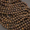 A pile of small, round wooden beads with a natural brown and tan grain, arranged on a dark gray background.