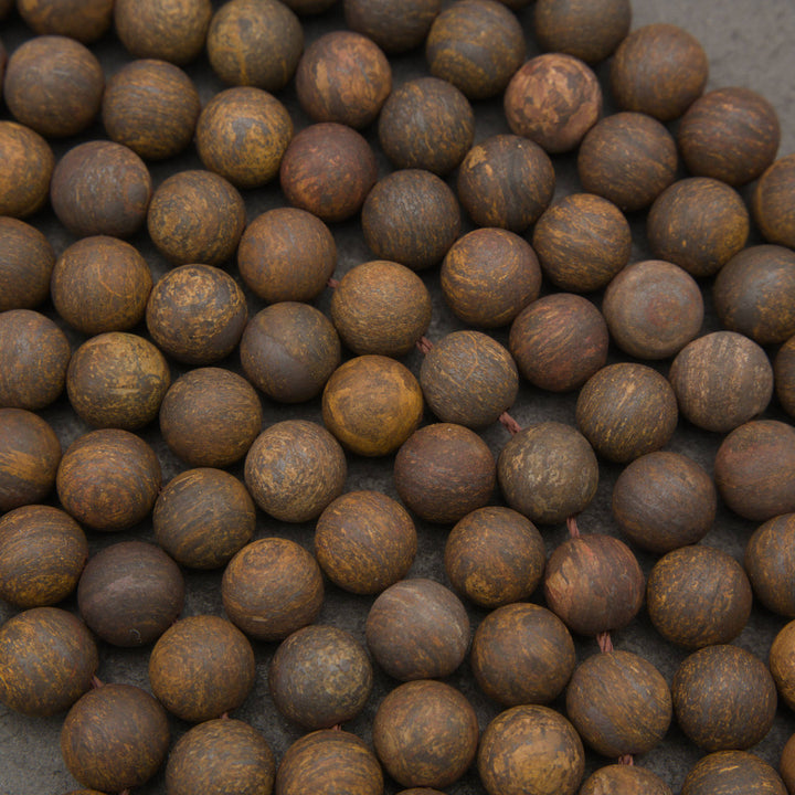 A close-up pile of round wooden beads with a natural, swirling grain pattern in shades of brown and tan.