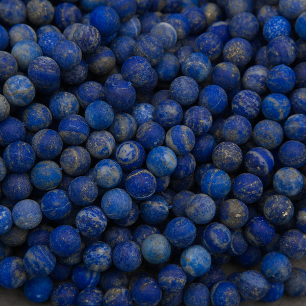 A close-up pile of small round blue beads with natural white and gray marbling, filling the entire frame.