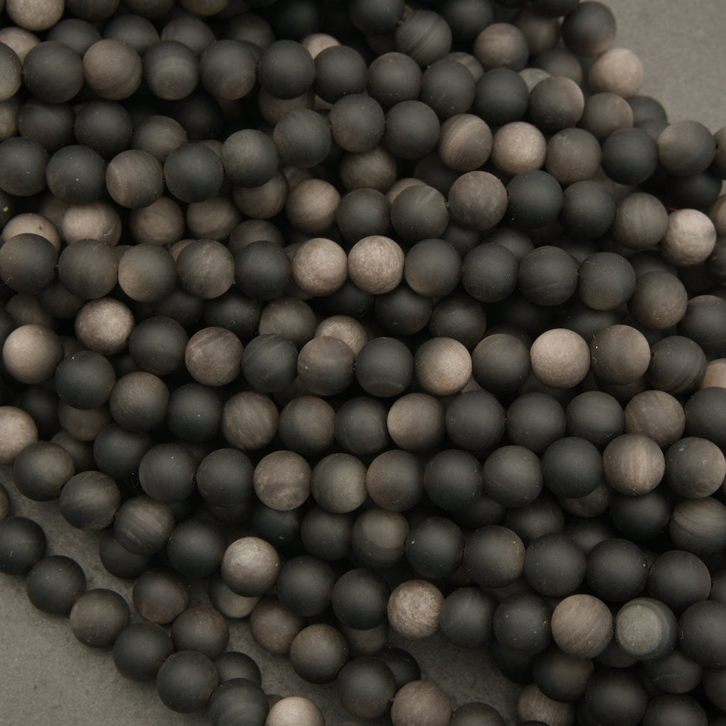 Close-up of black and gray spherical beads on a textured surface
