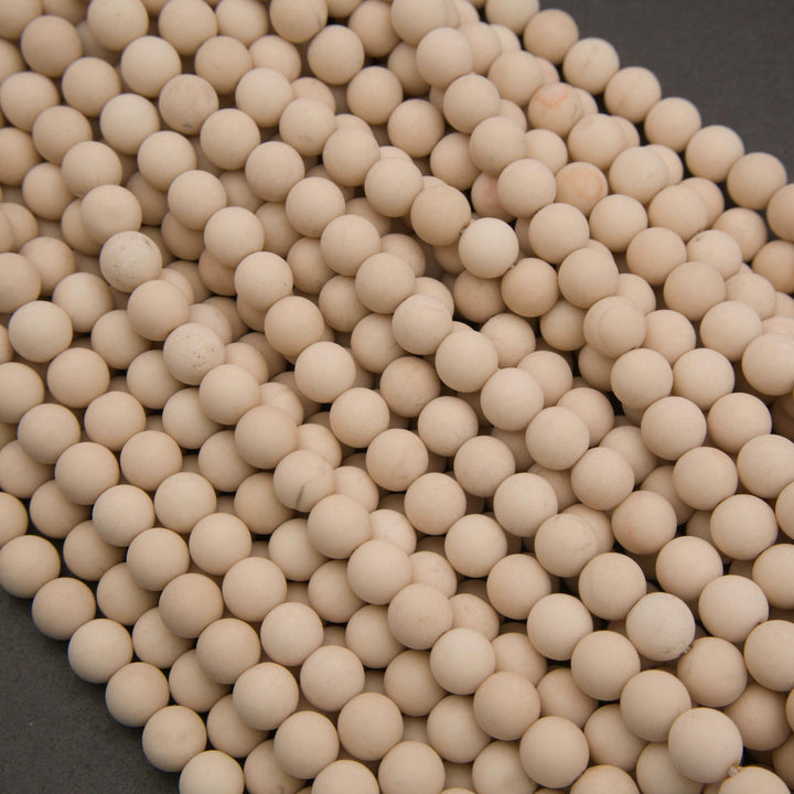 A pile of small, uniform beige ceramic beads or balls on a dark gray background.
