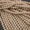 A close-up pile of small, round, off-white ceramic beads or balls filling the frame against a dark gray background.