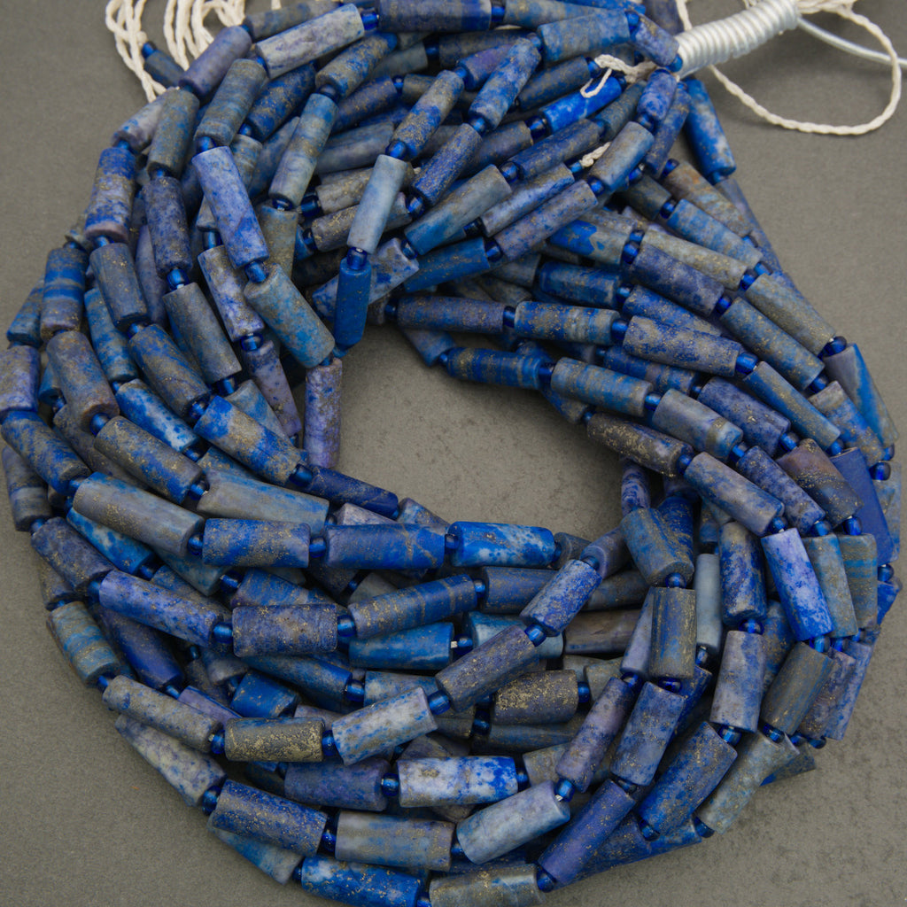 Coiled necklace with blue cylindrical beads on a gray background