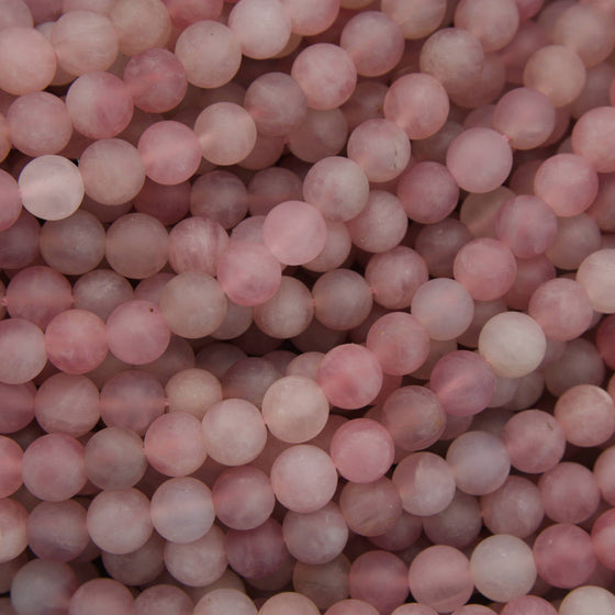 A close-up pile of round, matte pink beads with a soft, semi-translucent finish.
