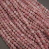 A close-up pile of round, pale pink beads with subtle white marbling, filling almost the entire frame against a dark gray background.
