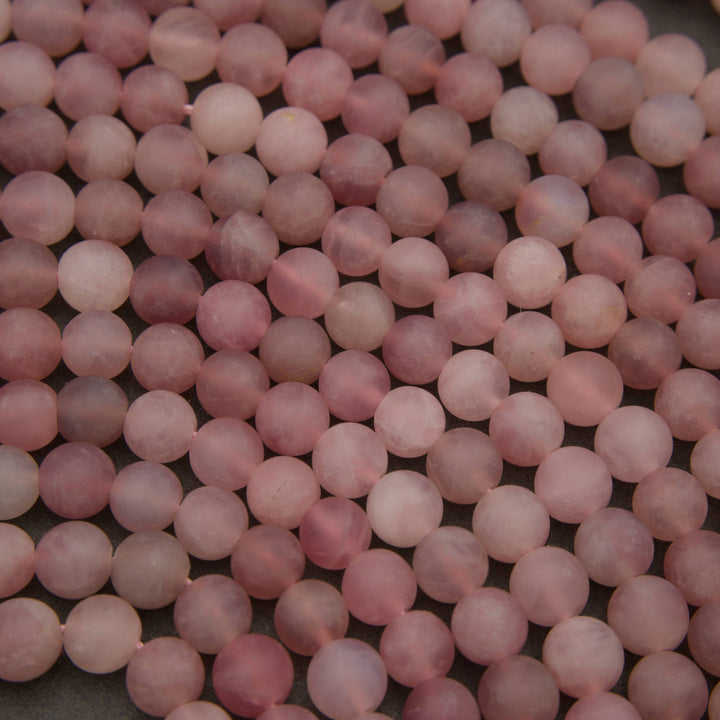A close-up pile of round, matte pink beads, likely rose quartz, filling the entire frame.
