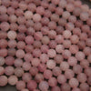 A close-up pile of round, matte pink beads, likely rose quartz, filling the entire frame.