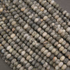 A close-up pile of small oval beads with a marbled stone pattern in shades of gray, beige, and white.