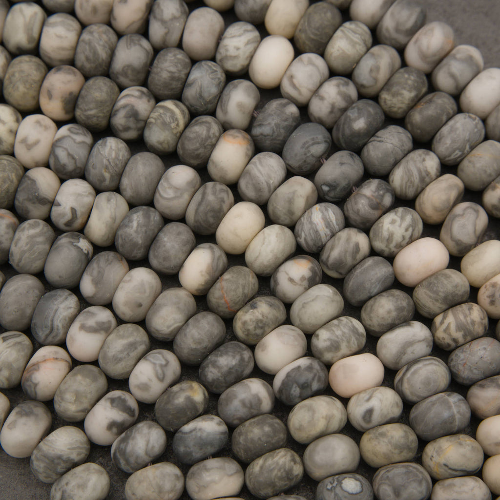 A close-up pile of smooth, rounded pebble-shaped beads in natural stone colors, featuring marbled patterns of gray, beige, white, and brown.