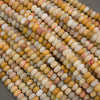 Close-up of multiple strands of polished cylindrical beads in a marbled mix of cream, yellow, orange, pink, and gray tones.