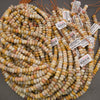 Multiple strands of small cylindrical beads in a marbled mix of cream, yellow, orange, pink, and gray tones, with some product tags visible.