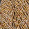 Multiple strands of small cylindrical beads in a marbled mix of cream, yellow, orange, pink, and gray tones, with some product tags visible.