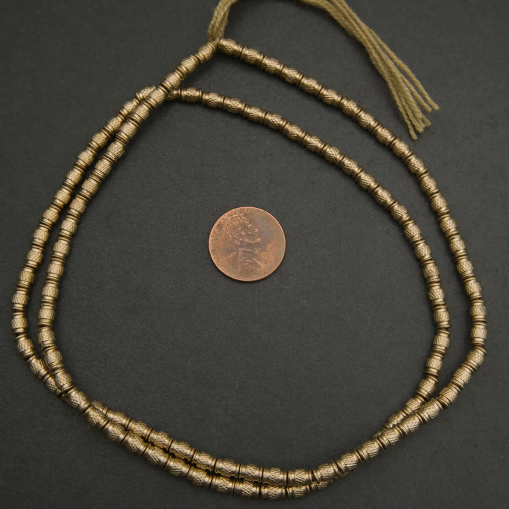 Bronze beaded necklace on a dark surface with a coin for scale