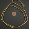 Bronze beaded necklace on a dark surface with a coin for scale