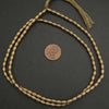 Bronze beaded necklace on a dark surface with a coin for scale