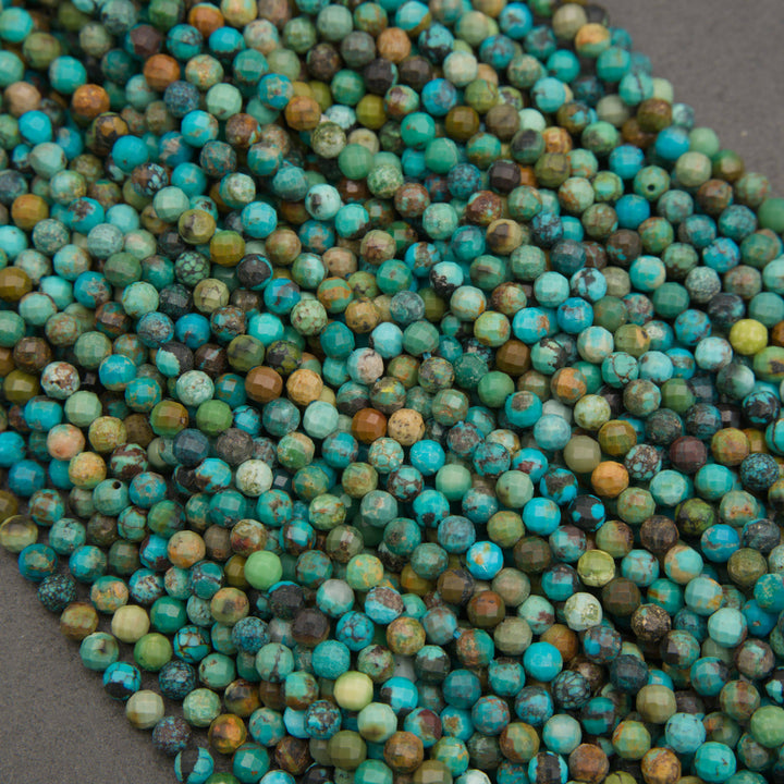 A close-up pile of faceted round beads in a mottled turquoise, teal, green, blue, and brown colorway, resting on a dark gray surface.