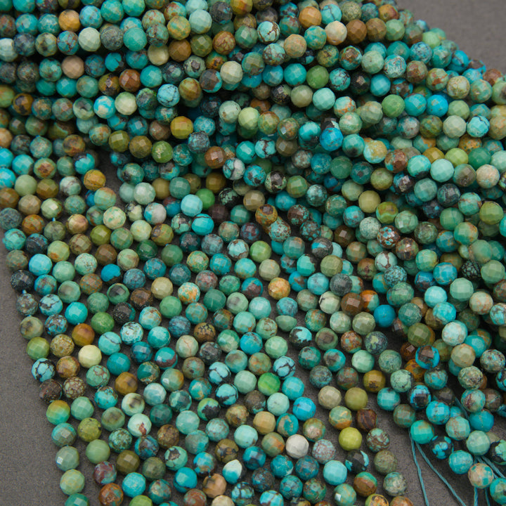 A close-up pile of round turquoise beads with natural mottled patterns in shades of blue, green, and brown, arranged on a neutral gray surface.