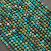 A close-up pile of faceted round beads in a mottled turquoise, teal, green, brown, and cream stone pattern, arranged on a dark gray surface.
