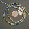 Multicolored bead necklace with a penny for scale on a gray background