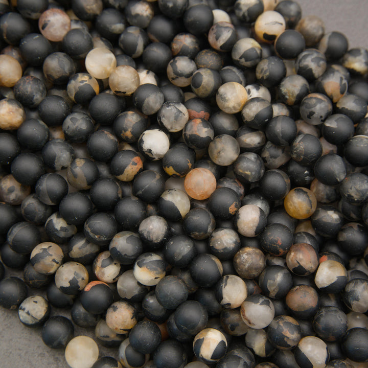 Close-up of calico tourmaline gemstone beads with a smooth matte finish and contrasting earthy mineral inclusions.