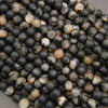 Close-up of calico tourmaline gemstone beads with a smooth matte finish and contrasting earthy mineral inclusions.
