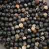 Multiple strands of matte calico tourmaline round beads displaying unique black, white, beige, and orange color variations.