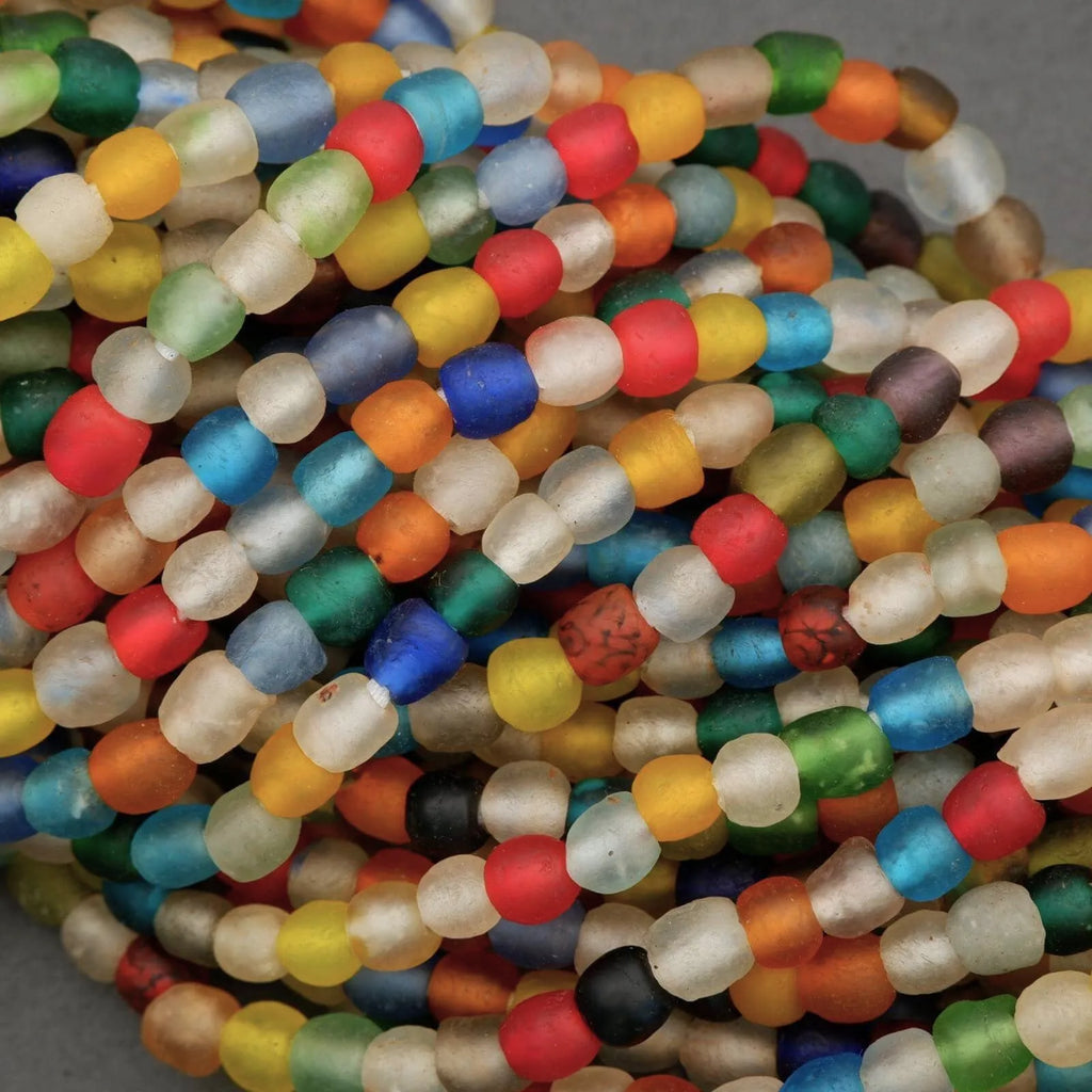 Colorful glass beads in various shapes and sizes on a gray background
