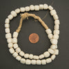 String of white beads with a penny for scale on a dark background