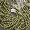 Close-up of matte Russian Serpentine beads with varied olive and yellow-green patterns