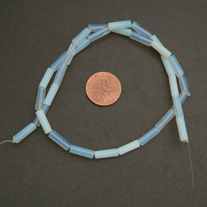String of light blue beads with a penny for scale on a dark surface