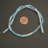 String of light blue beads with a penny for scale on a dark surface
