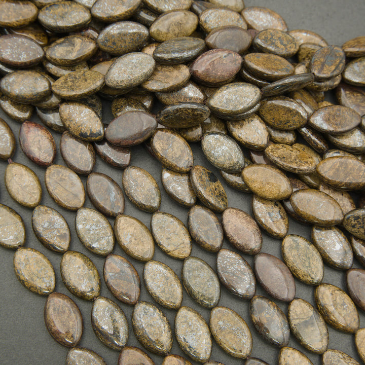 Close-up of oval-shaped stones in various shades of brown and gray on a dark surface.