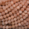 Matte peach moonstone round beads featuring soft pink, peach, and apricot tones with delicate white streaks.