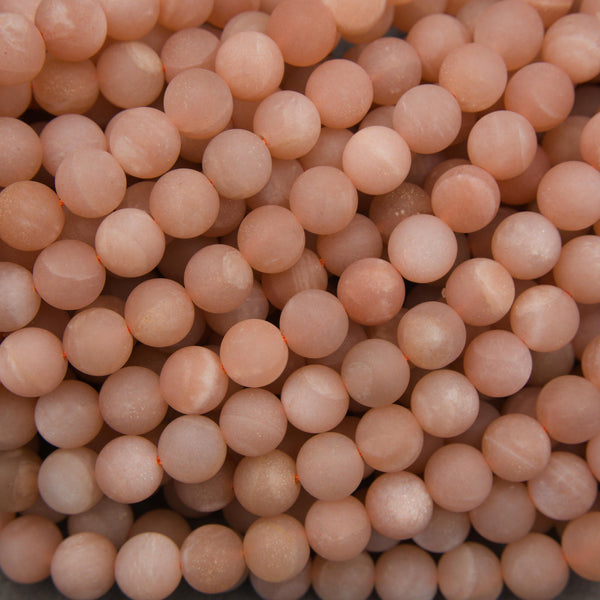 Matte peach moonstone round beads featuring soft pink, peach, and apricot tones with delicate white streaks.