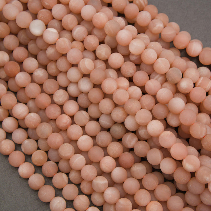 Close-up of natural peach moonstone gemstone beads with a frosted matte finish and subtle pearly shimmer.